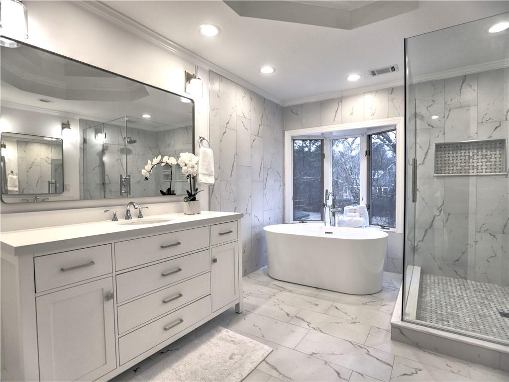 Bathroom with vanity, plus walk in shower, a tray ceiling, tile floors, and ornamental molding