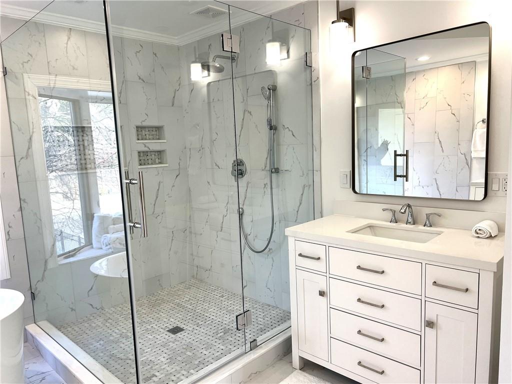 Bathroom with a healthy amount of sunlight, an enclosed shower, and vanity
