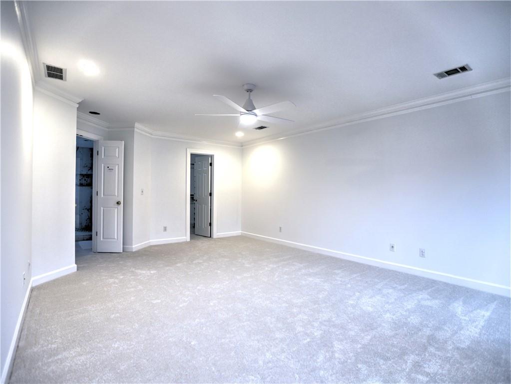Primary Bedroom with molding, new light colored carpet, and ceiling fan