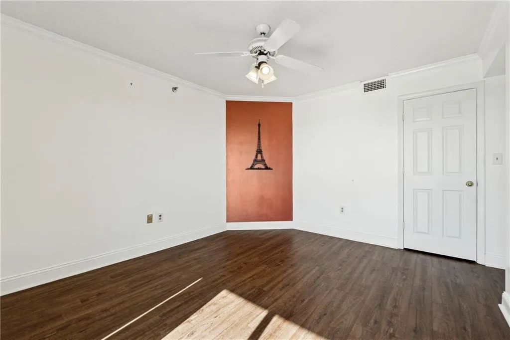 Unfurnished room featuring ceiling fan, dark hardwood / wood-style flooring, and ornamental molding