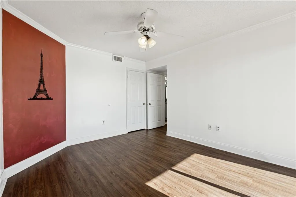 Unfurnished room with a textured ceiling, dark hardwood / wood-style flooring, ceiling fan, and ornamental molding