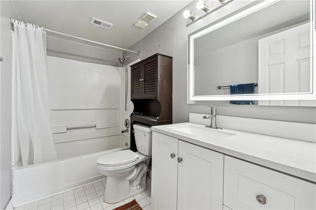 Full bathroom with toilet, vanity, tile patterned floors, and shower / bath combo with shower curtain