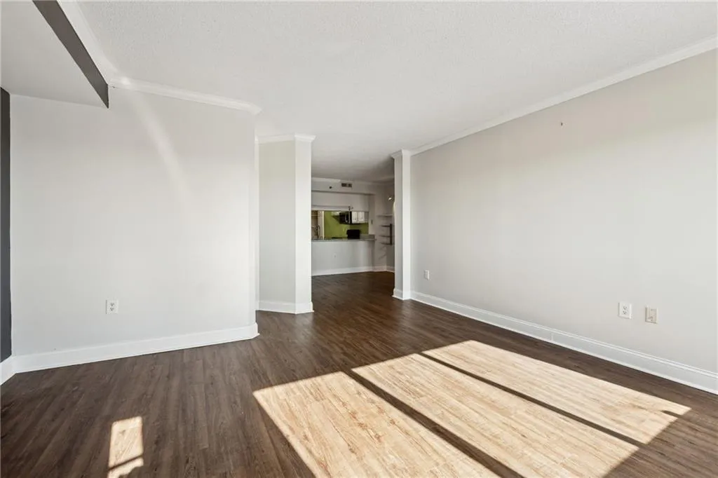 Spare room with dark wood-type flooring and ornamental molding