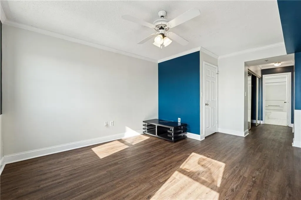 Unfurnished living room with a textured ceiling, dark hardwood / wood-style floors, ceiling fan, and ornamental molding