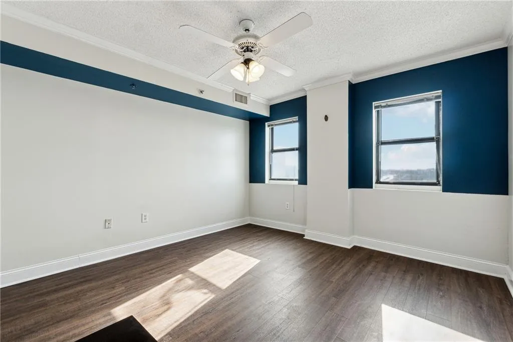 Unfurnished room with ceiling fan, dark hardwood / wood-style floors, crown molding, and a textured ceiling