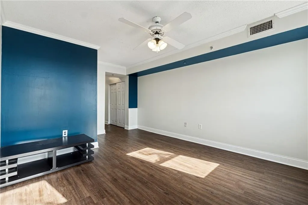 Empty room featuring a textured ceiling, ceiling fan, dark hardwood / wood-style flooring, and crown molding