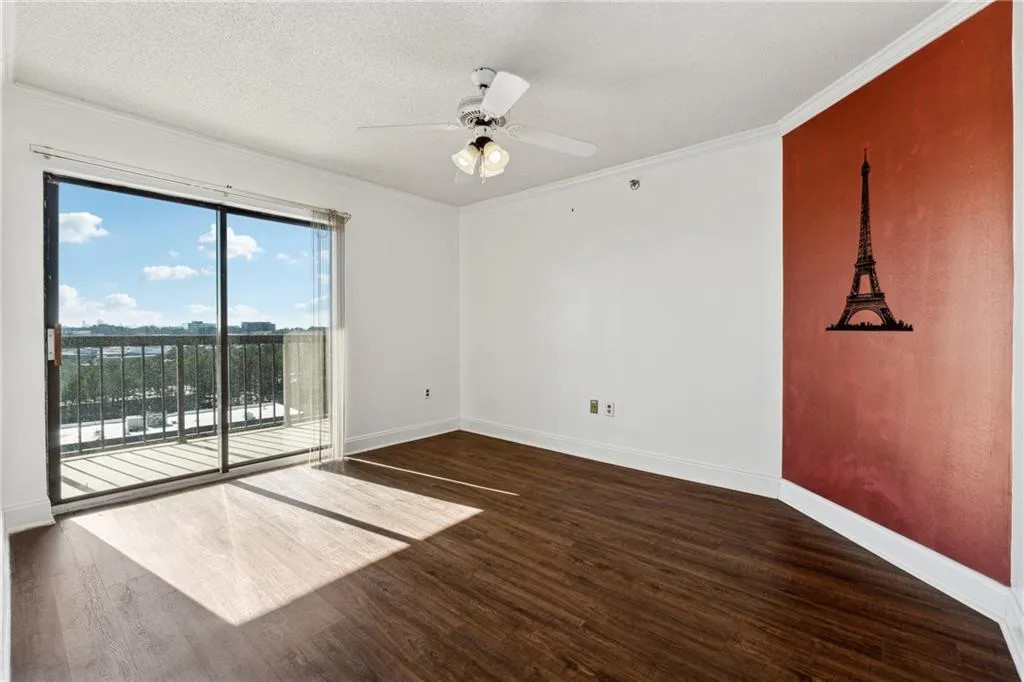 Spare room with a textured ceiling, ceiling fan, ornamental molding, and dark wood-type flooring