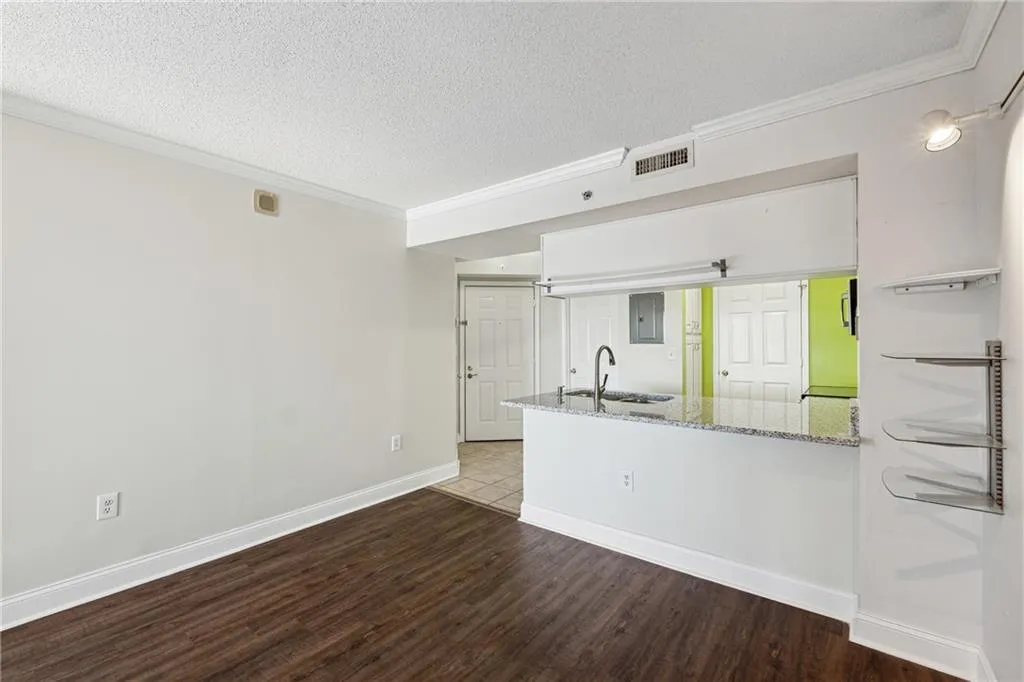 Kitchen with light stone counters, a textured ceiling, sink, wood-type flooring, and white cabinetry