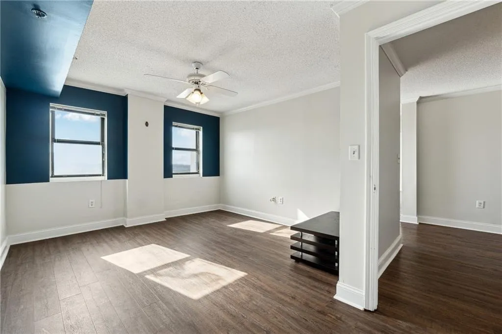 Unfurnished room featuring a textured ceiling, ceiling fan, dark hardwood / wood-style flooring, and crown molding