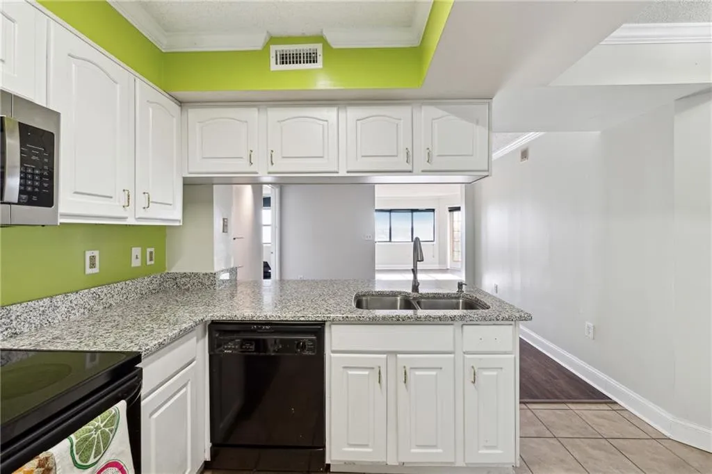 Kitchen with kitchen peninsula, black dishwasher, and white cabinetry