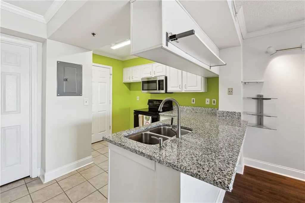 Kitchen featuring kitchen peninsula, stainless steel appliances, crown molding, white cabinets, and electric panel