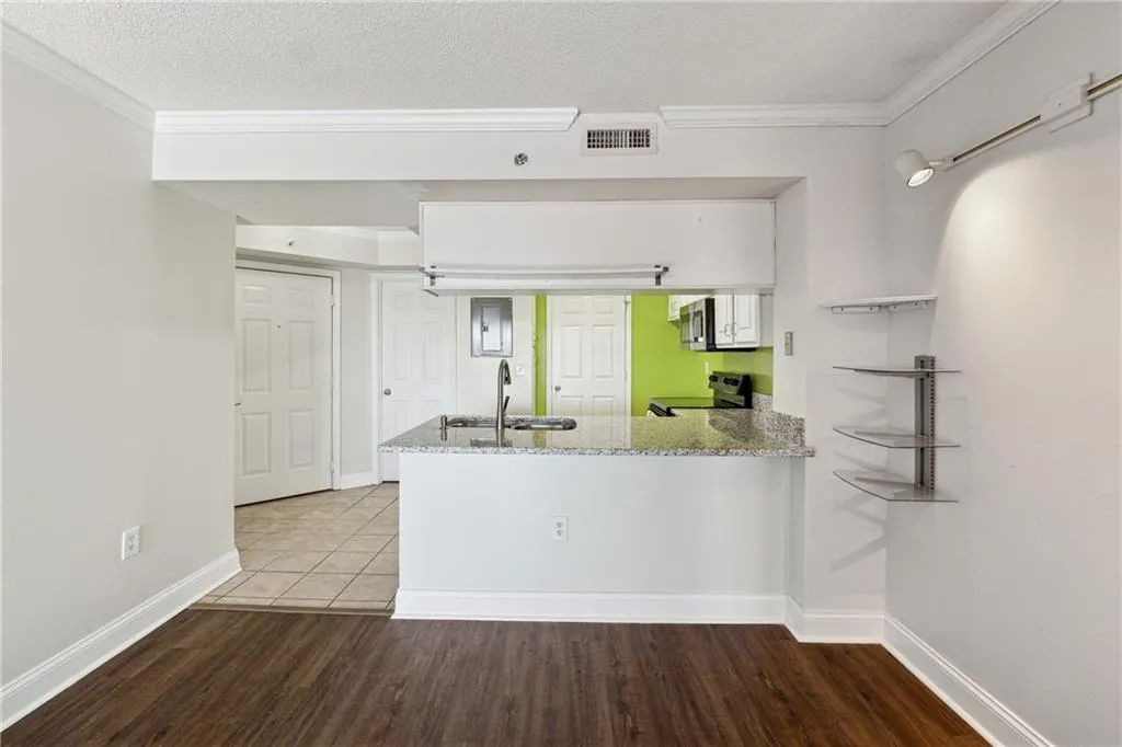 Kitchen with hardwood / wood-style floors, sink, light stone countertops, appliances with stainless steel finishes, and kitchen peninsula