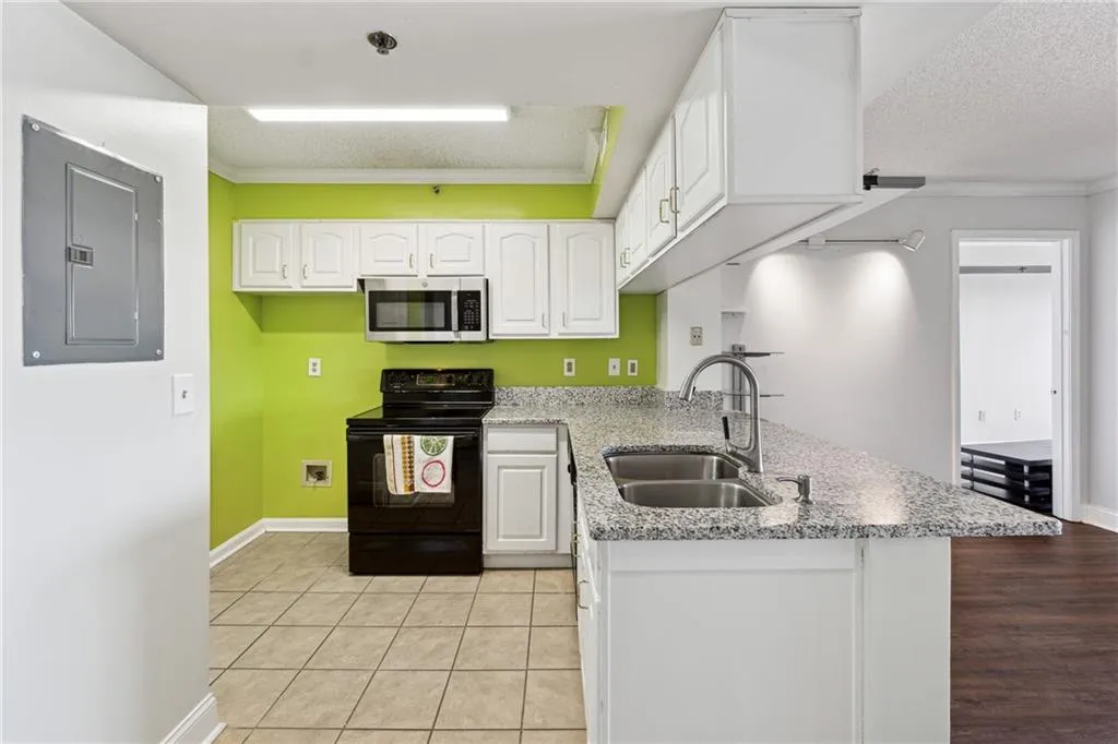Kitchen with ornamental molding, sink, white cabinets, electric panel, and black range with electric stovetop