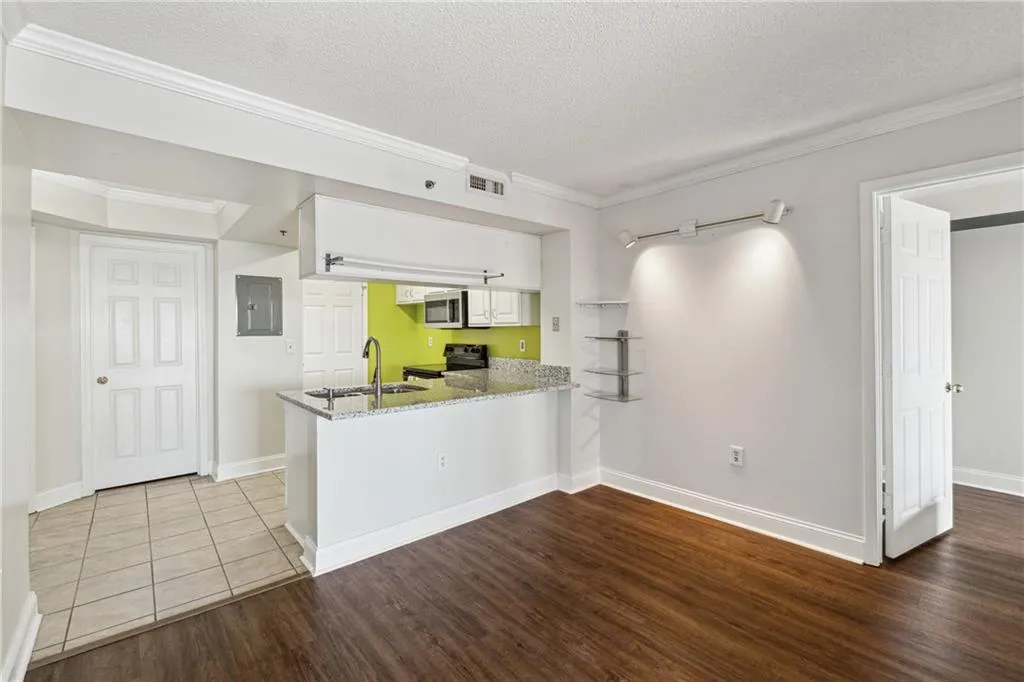Kitchen featuring white cabinets, kitchen peninsula, black electric range, and sink