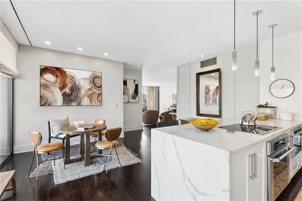 Kitchen featuring stainless steel appliances, dark wood-type flooring, light stone counters, white cabinets, and open floor plan