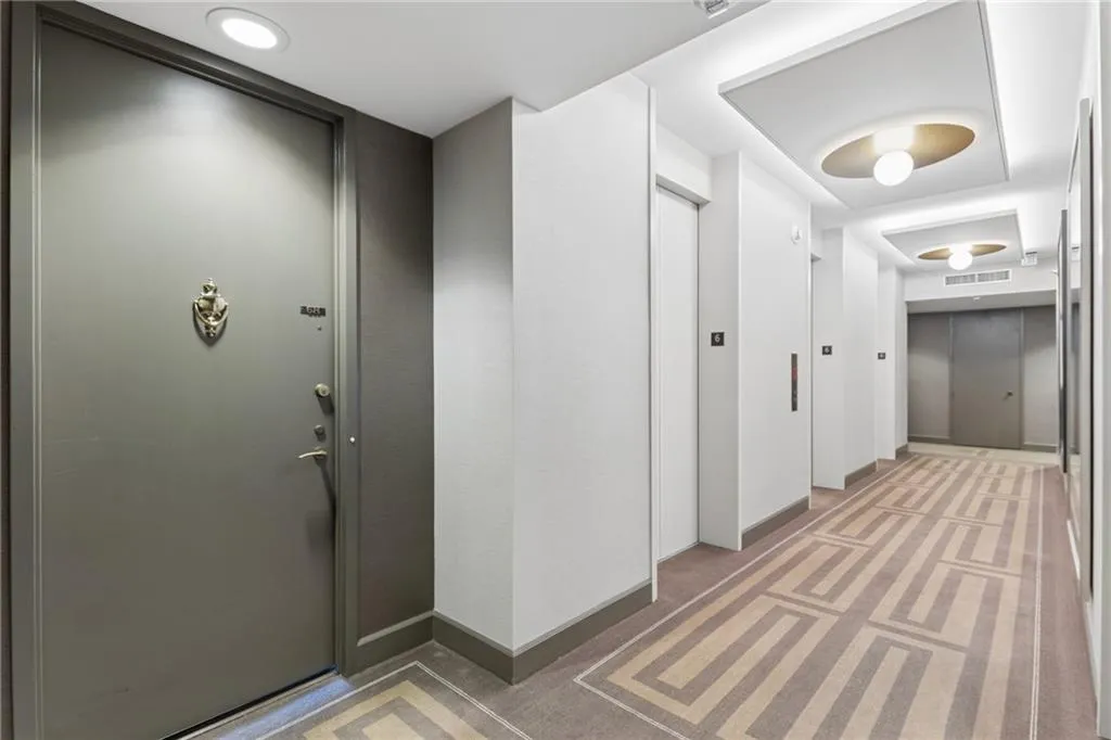 Hallway with light carpet and elevator