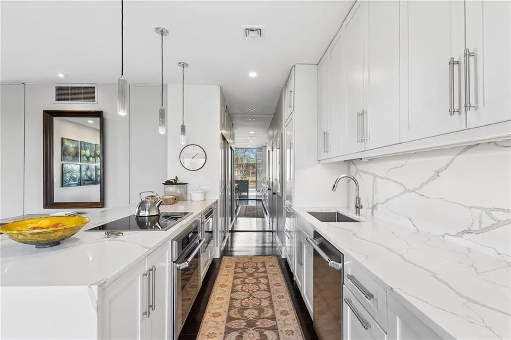 Kitchen featuring white cabinets, light stone countertops, a peninsula, and stainless steel appliances