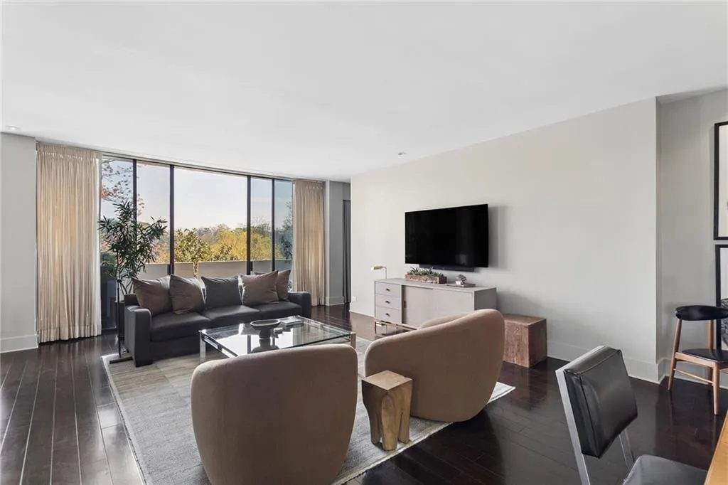 Living room with floor to ceiling windows and dark wood-style flooring