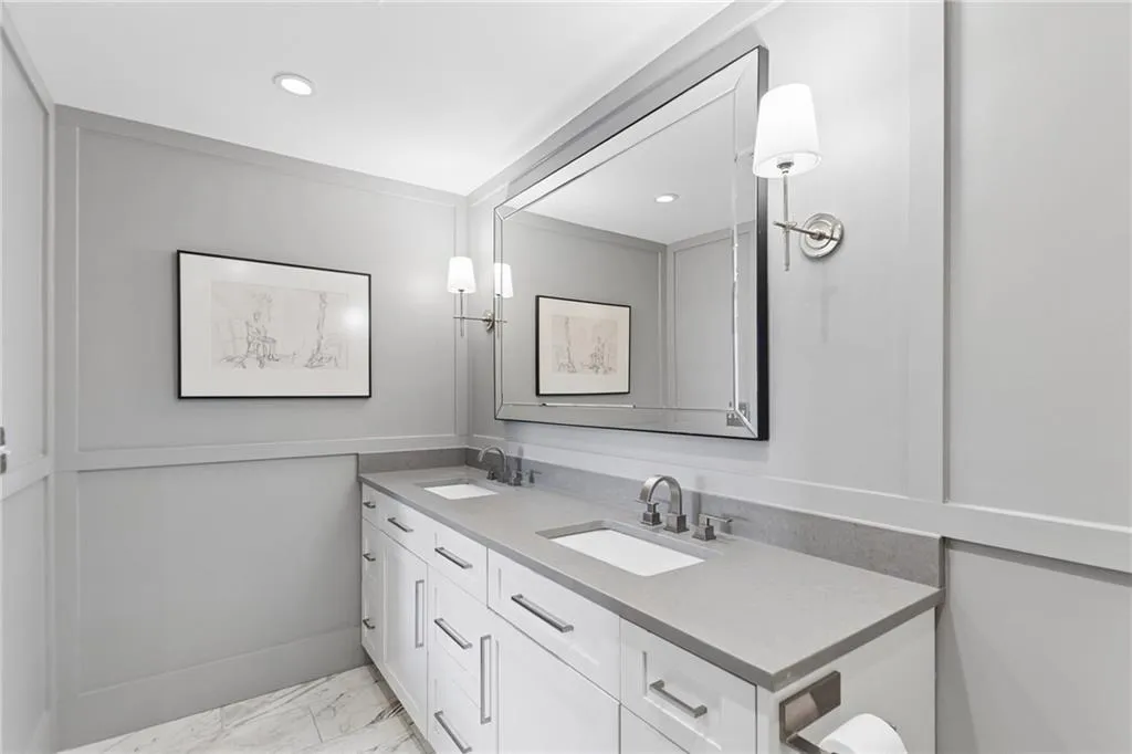 Bathroom featuring double vanity and light marble finish floors