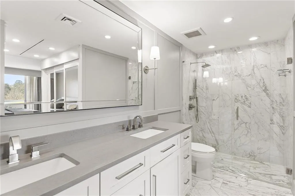 Full bathroom with double vanity, a marble finish shower, recessed lighting, and light marble finish floors
