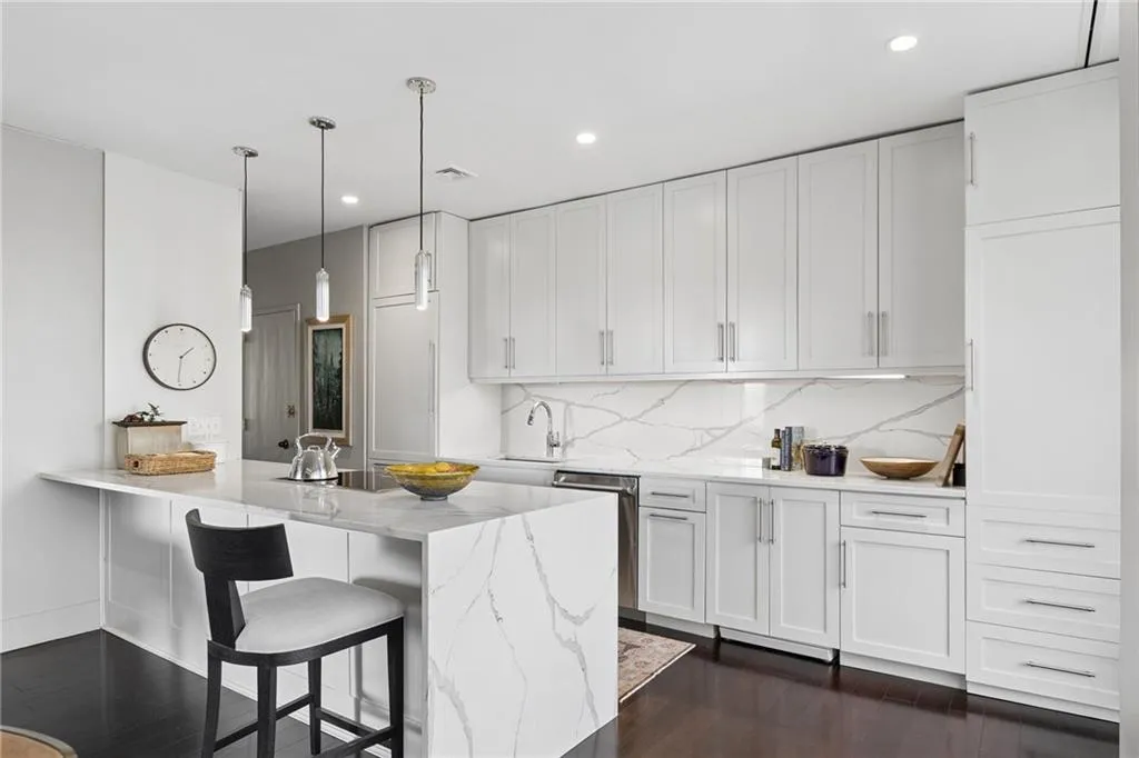 Kitchen with light stone counters, a kitchen breakfast bar, white cabinets, and a peninsula