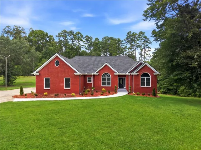 Red brick exterior with white trim, dark gray roof, arched windows, and a curved walkway to the front entry