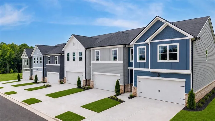 Modern townhome architecture featuring varied siding textures, attached garages, and individual driveway pads rendering