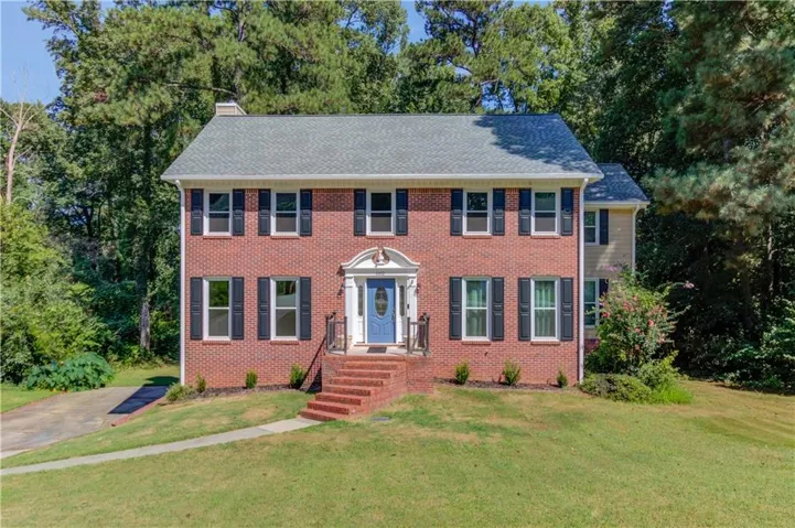 Traditional brick exterior, featuring a symmetrical facade, dark window shutters, a prominent front entry with a portico, and a multi-level roofline