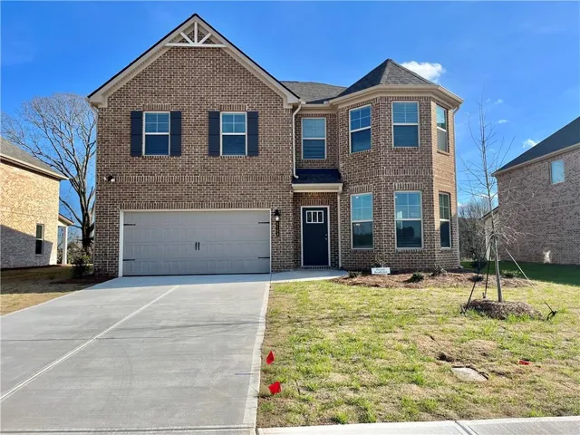 Brick exterior residence featuring a two-car garage, multiple large windows, and a covered entry