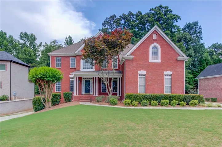 Grand brick facade with white trim accents and a columned front porch