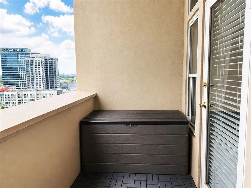 Balcony featuring textured wall, tile flooring, and glass door with blinds