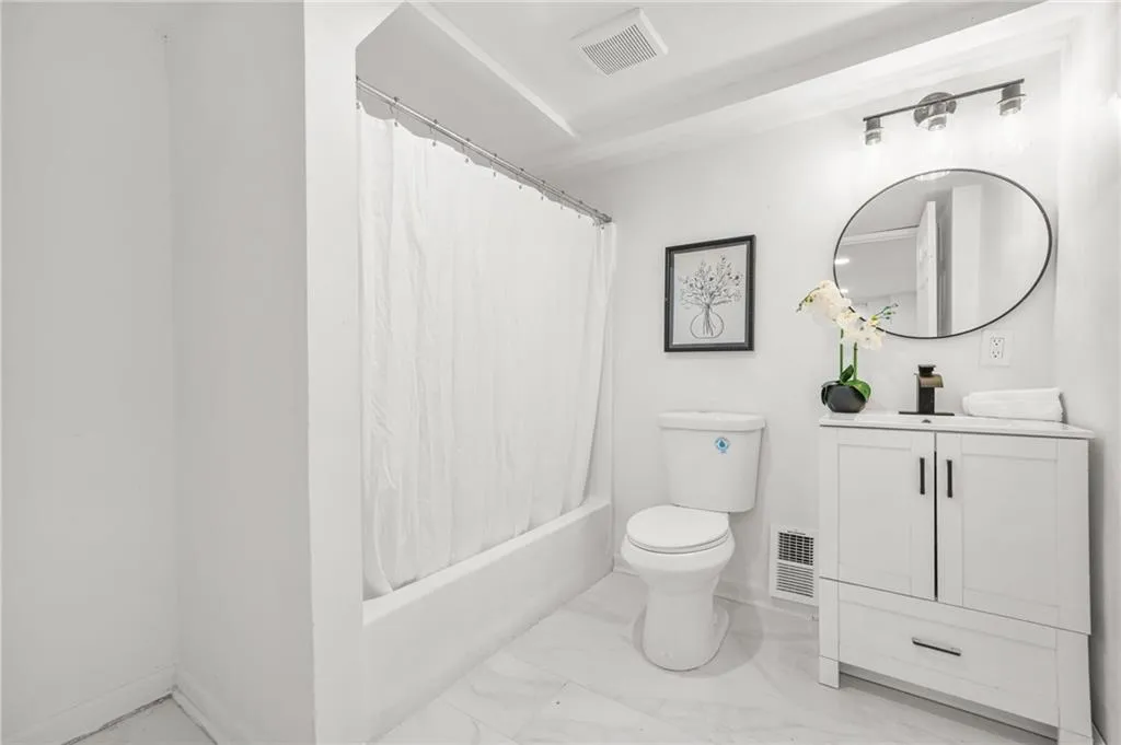 Bath - Lower LevelBathroom featuring vanity, marble look tiles, and shower / tub combo with curtain