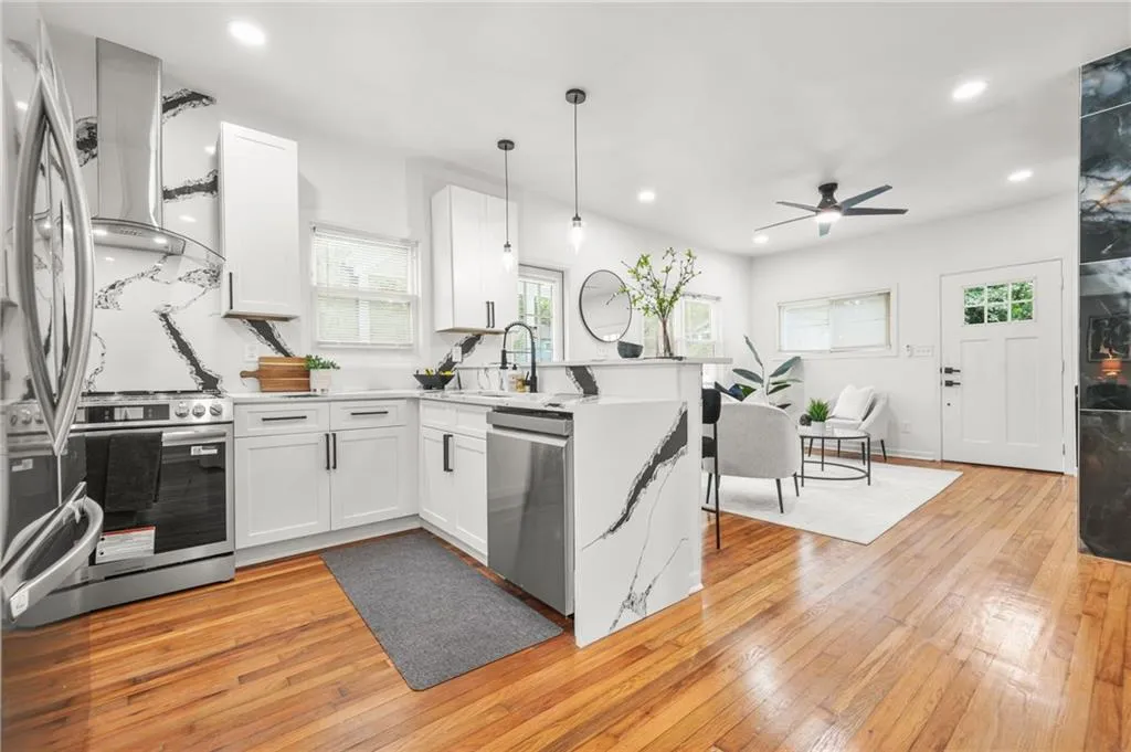Kitchen featuring a peninsula, appliances with stainless steel finishes, recessed lighting, light countertops, and wall chimney range hood
