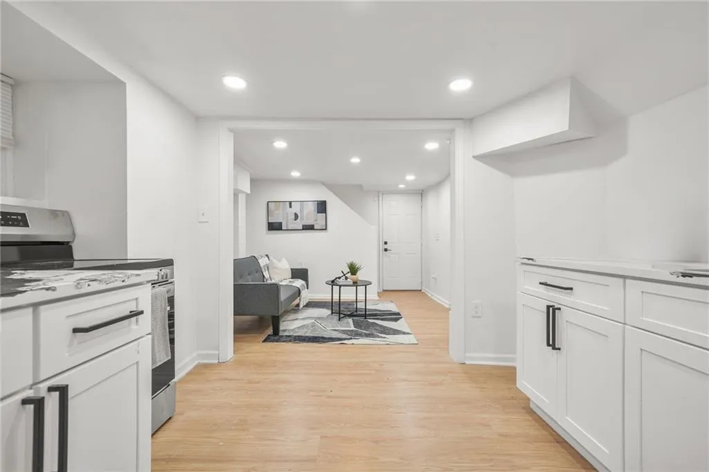 Kitchen with electric stove, light wood-type flooring, white cabinetry, recessed lighting, and light countertops