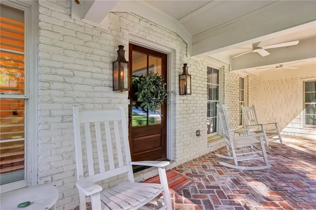 Entrance to property featuring ceiling fan and brick siding