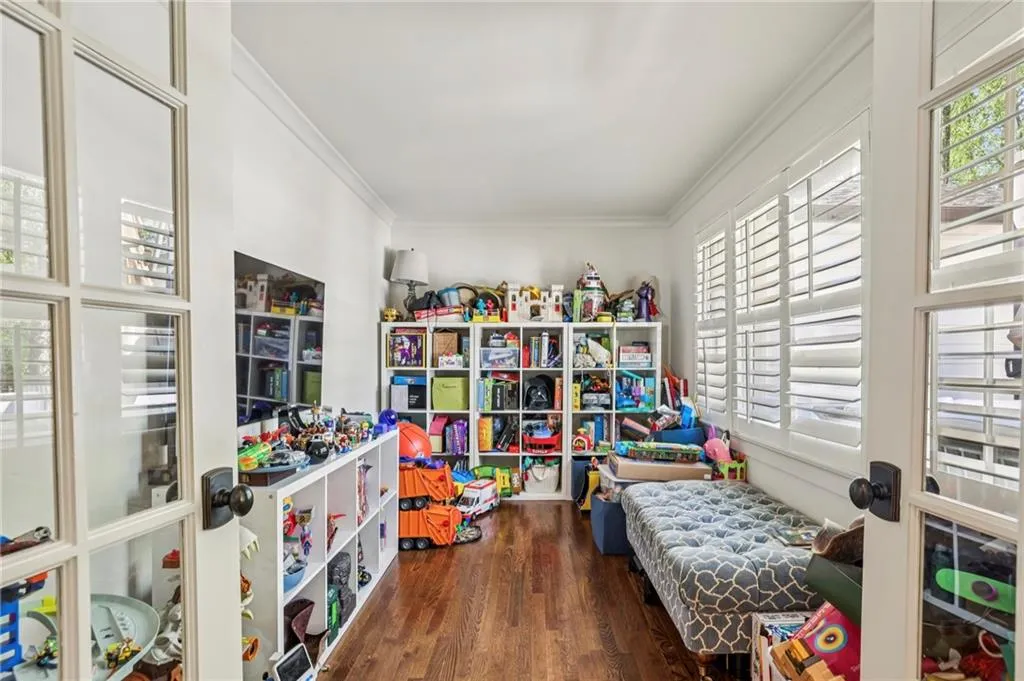 Recreation room with healthy amount of natural light, dark wood finished floors, ornamental molding, and french doors
