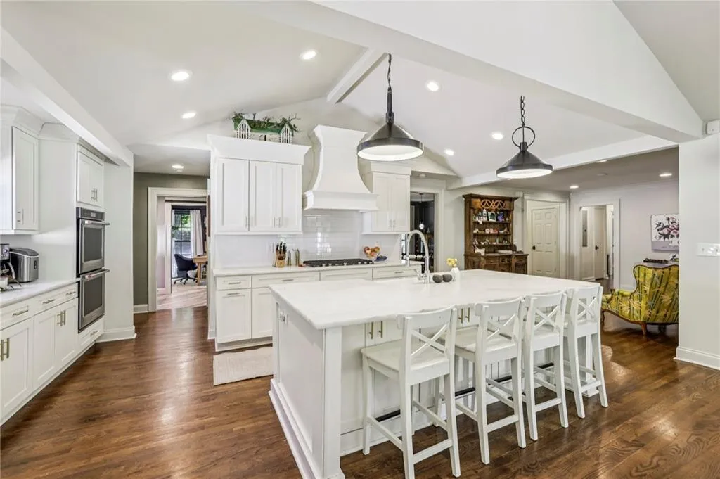 Kitchen with decorative light fixtures, white cabinets, a breakfast bar, and dark wood finished floors