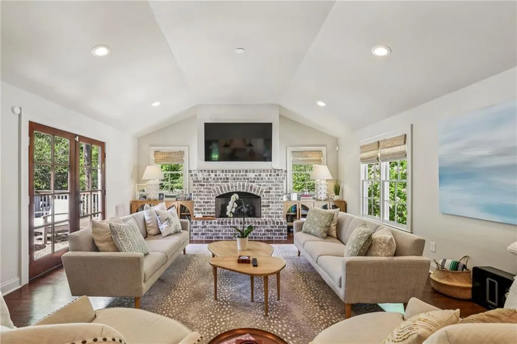 Living room with a brick fireplace, wood finished floors, and recessed lighting
