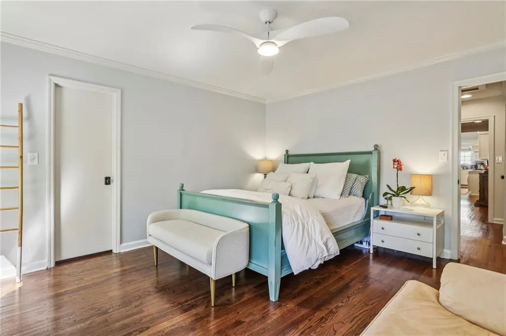 Bedroom featuring dark wood-type flooring, ornamental molding, and ceiling fan