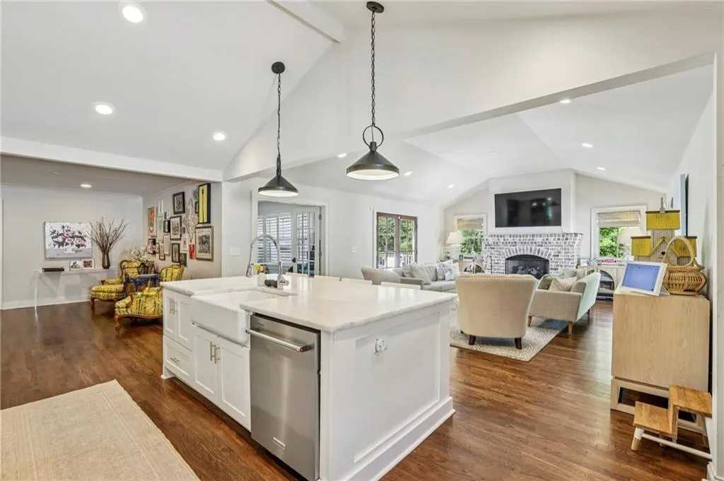 Kitchen featuring open floor plan, dishwasher, decorative light fixtures, dark wood finished floors, and a kitchen island with sink