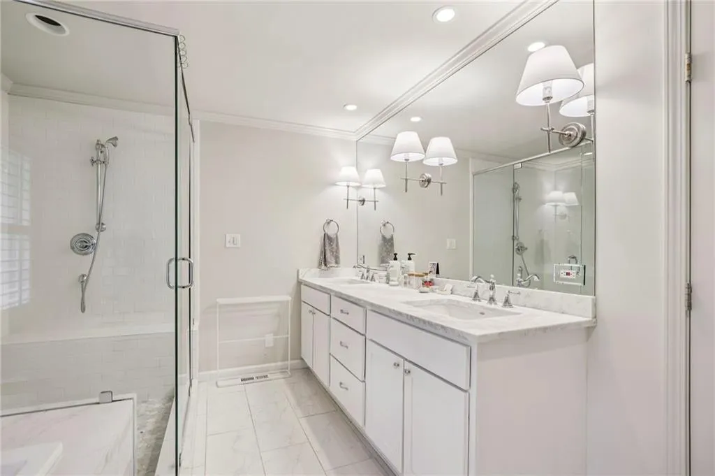 Bathroom with double vanity, a shower stall, recessed lighting, light marble finish floors, and crown molding