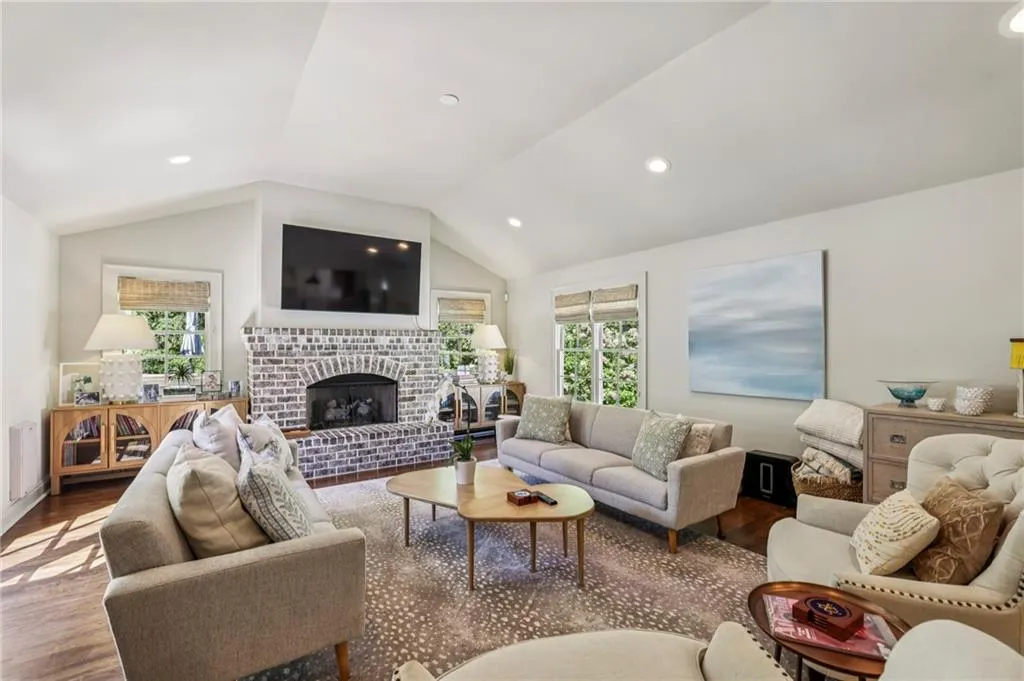Living room featuring wood finished floors, a fireplace, lofted ceiling, and recessed lighting