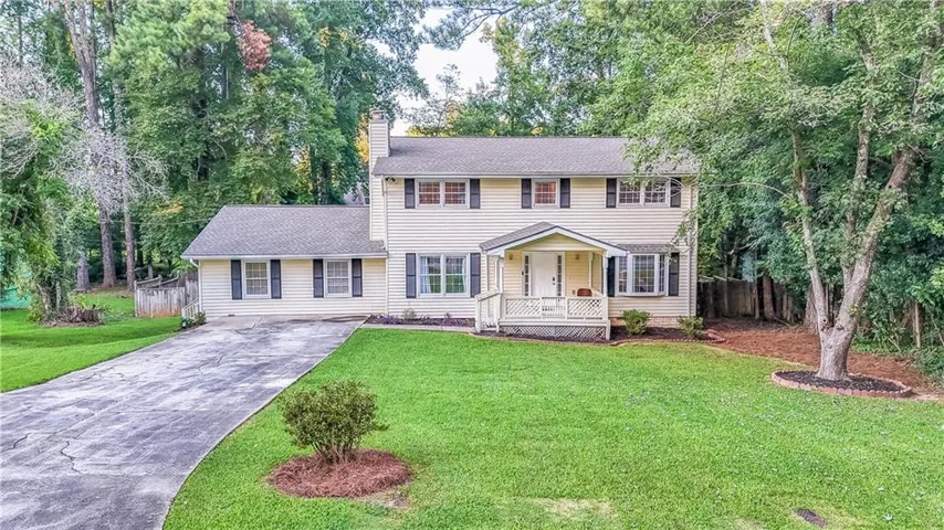 Traditional home with a covered front porch, bay window, and a paved driveway
