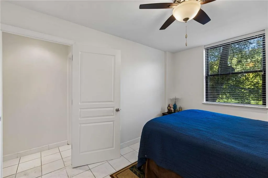 Room featuring white tile flooring, a multi-panel interior door, and a ceiling fan with integrated lighting