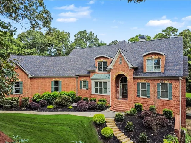 Brick exterior with arched entryway, dormer windows, and a multi-pitch roof