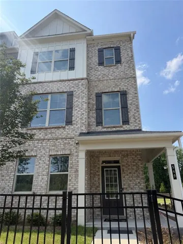 Three-story townhome featuring a brick facade with complementary board and batten siding