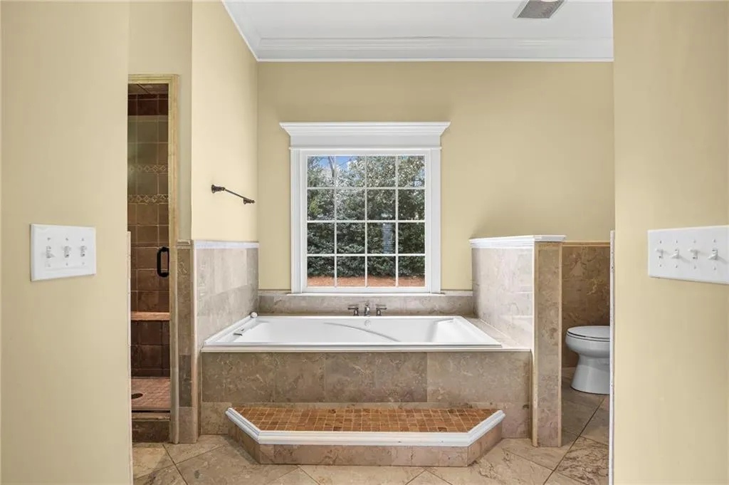 Full bath with ornamental molding, a garden tub, and a stall shower