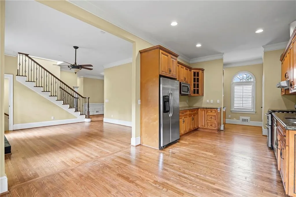 Kitchen featuring wood finish cabinets, ornamental molding, glass insert cabinets, stainless steel appliances, and dark stone counters