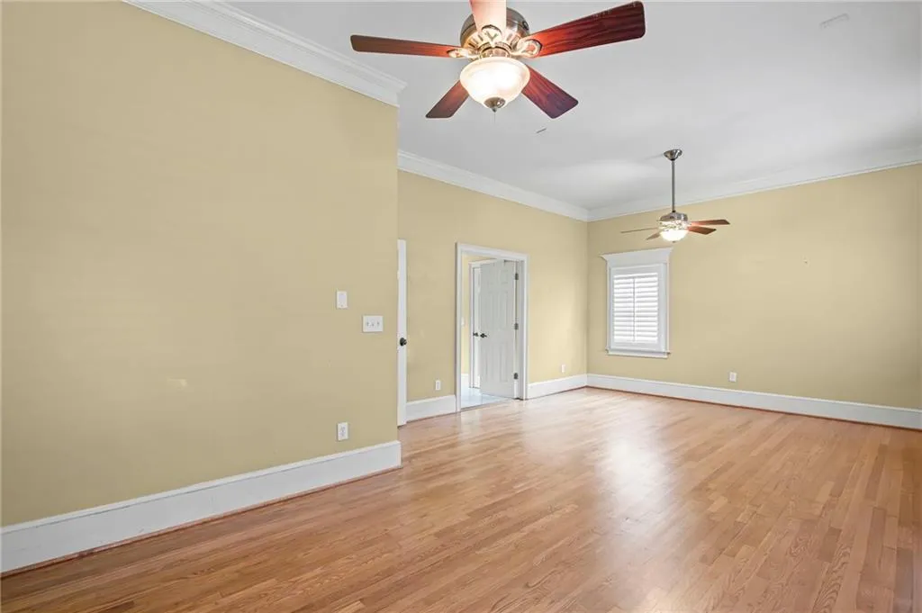 Spare room with crown molding, light wood-type flooring, and ceiling fan