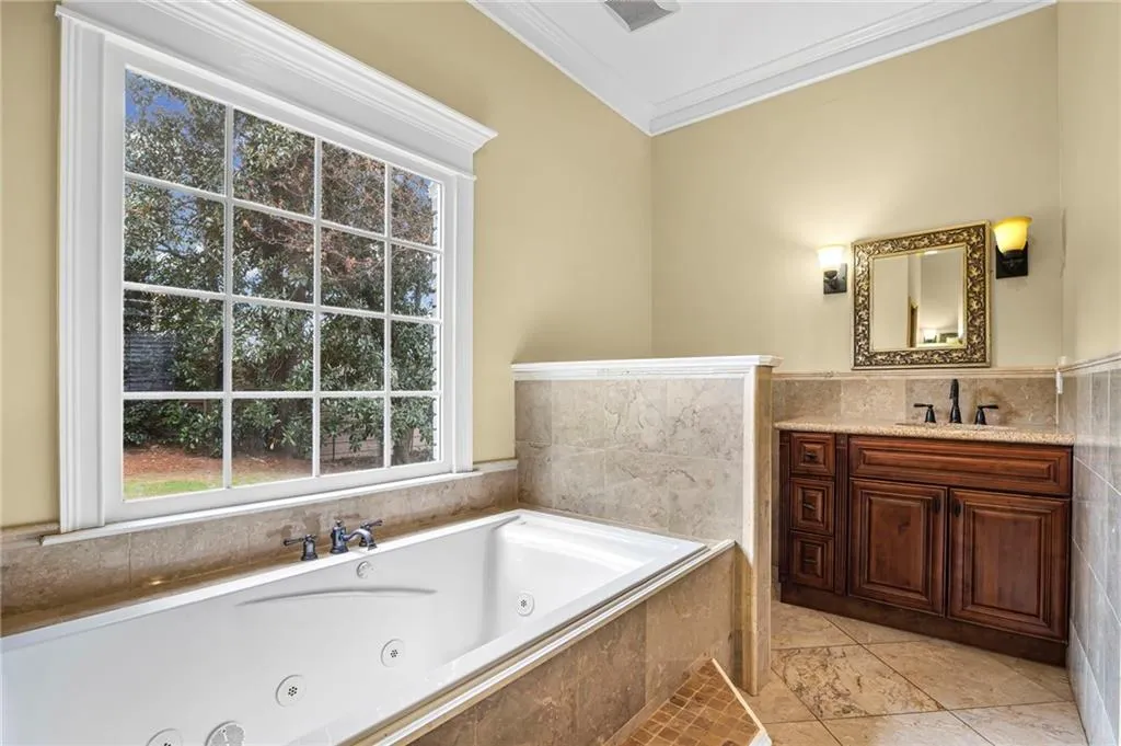 Full bath with vanity, ornamental molding, a whirlpool tub, tile walls, and wainscoting